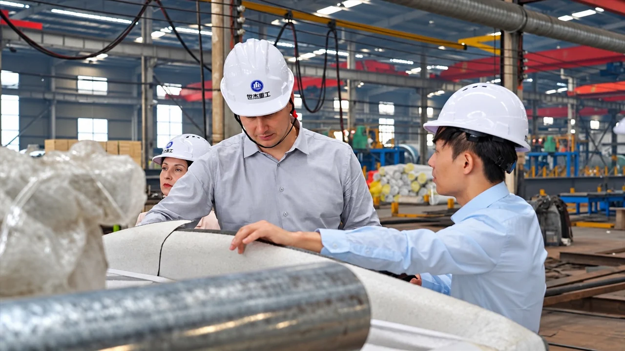 Visitors and supplier staff reviewing a large metal component in a factory workshop